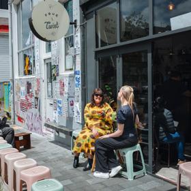 Two friends enjoy iced coffees on the exterior seating at Pour & Twist on a sunny day.