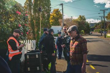 Behing the scenes of Wellington Paranormal, a comedic television series. The cast and crew are shooting a scene on a suburban street.