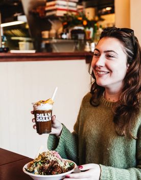 Person enjoying an iced coffee and fresh salad at Dilly Dally