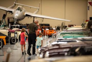 A grandpa and grandchildren walking through vintage  cars at the Southward Car Museum.