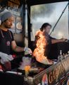 Chefs in a truck at the Harbourside Markets flame cooking noodles.