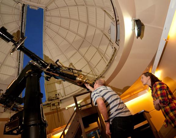 A person looking through the telescope at Space Place.