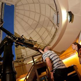 A person looking through the telescope at Space Place.
