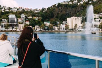 A person uses their cellphone to take a picture of the Carter Memorial Fountain at Oriental Bay from the East by West ferry in Wellignton.