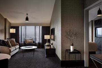 The lounge in a room at the Mövenpick Hotel with a two-seater couch, chair and round marble coffee table.