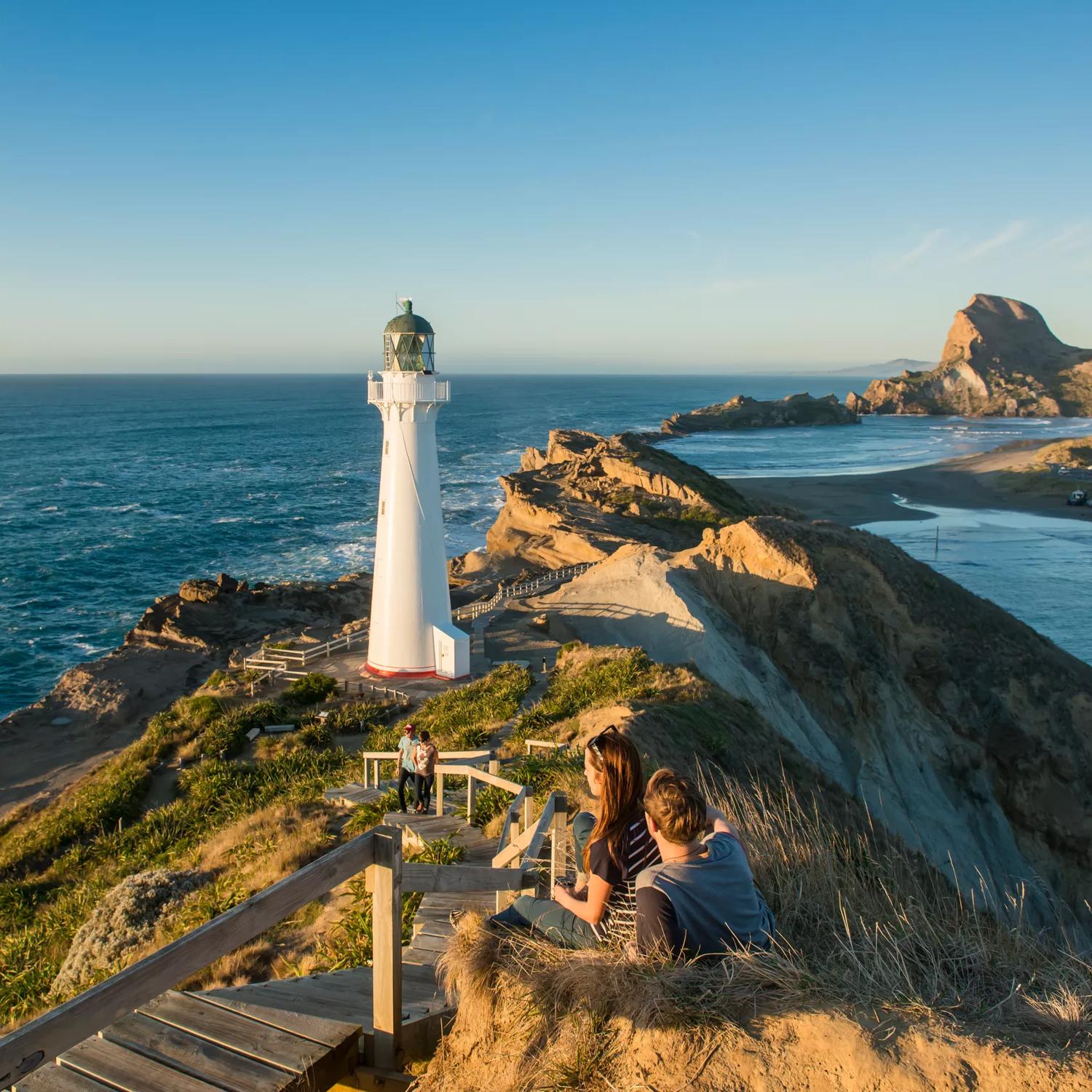 A couple sits beside the path toward Castlepoint Lighthouse to take in the view.