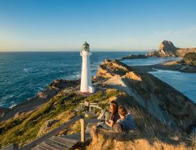 A couple sits beside the path toward Castlepoint Lighthouse to take in the view.