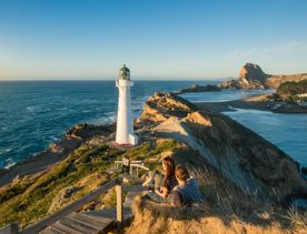 A couple sits beside the path toward Castlepoint Lighthouse to take in the view.
