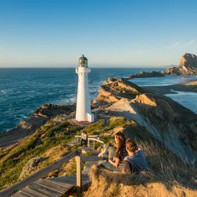 A couple sits beside the path toward Castlepoint Lighthouse to take in the view.