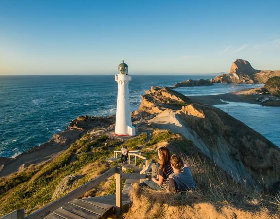 A couple sits beside the path toward Castlepoint Lighthouse to take in the view.