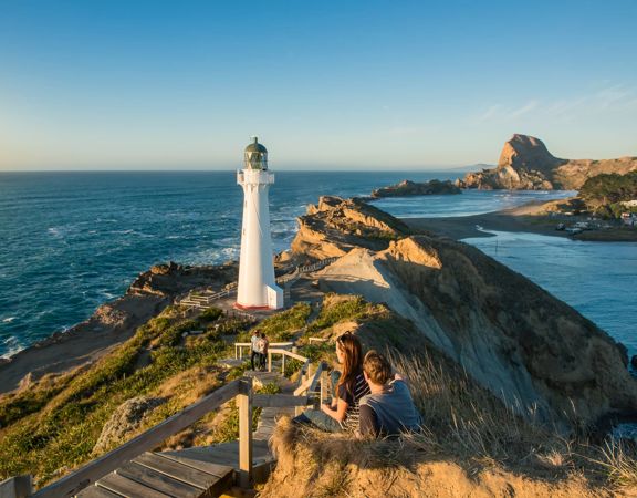 A couple sits beside the path toward Castlepoint Lighthouse to take in the view.