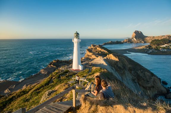 A couple sits beside the path toward Castlepoint Lighthouse to take in the view.