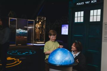 A child and mother play with a swirling orb at the Doctor Who exhibition.