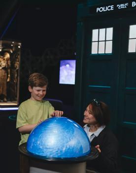 A child and mother play with a swirling orb at the Doctor Who exhibition.