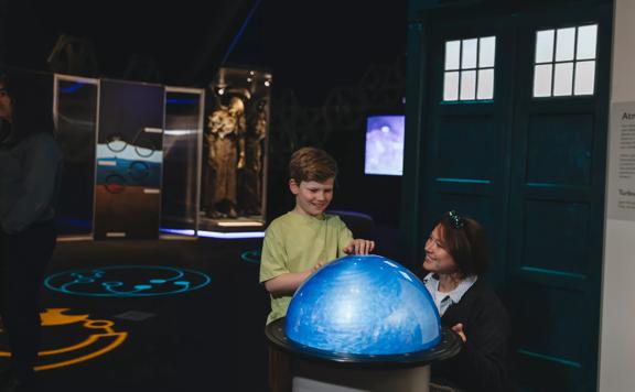 A child and mother play with a swirling orb at the Doctor Who exhibition.