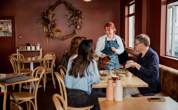 Waiter serving water to a group of people at August Eatery in Wellington.