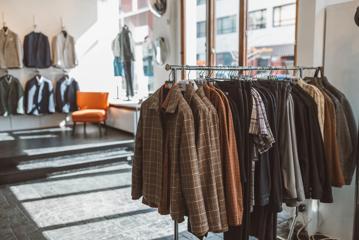 Inside Mandatory Menswear Ltd, a men's clothing store in Te Aro, Wellington. The modern space has white walls, black floors, large windows and suits hanging on a rack.