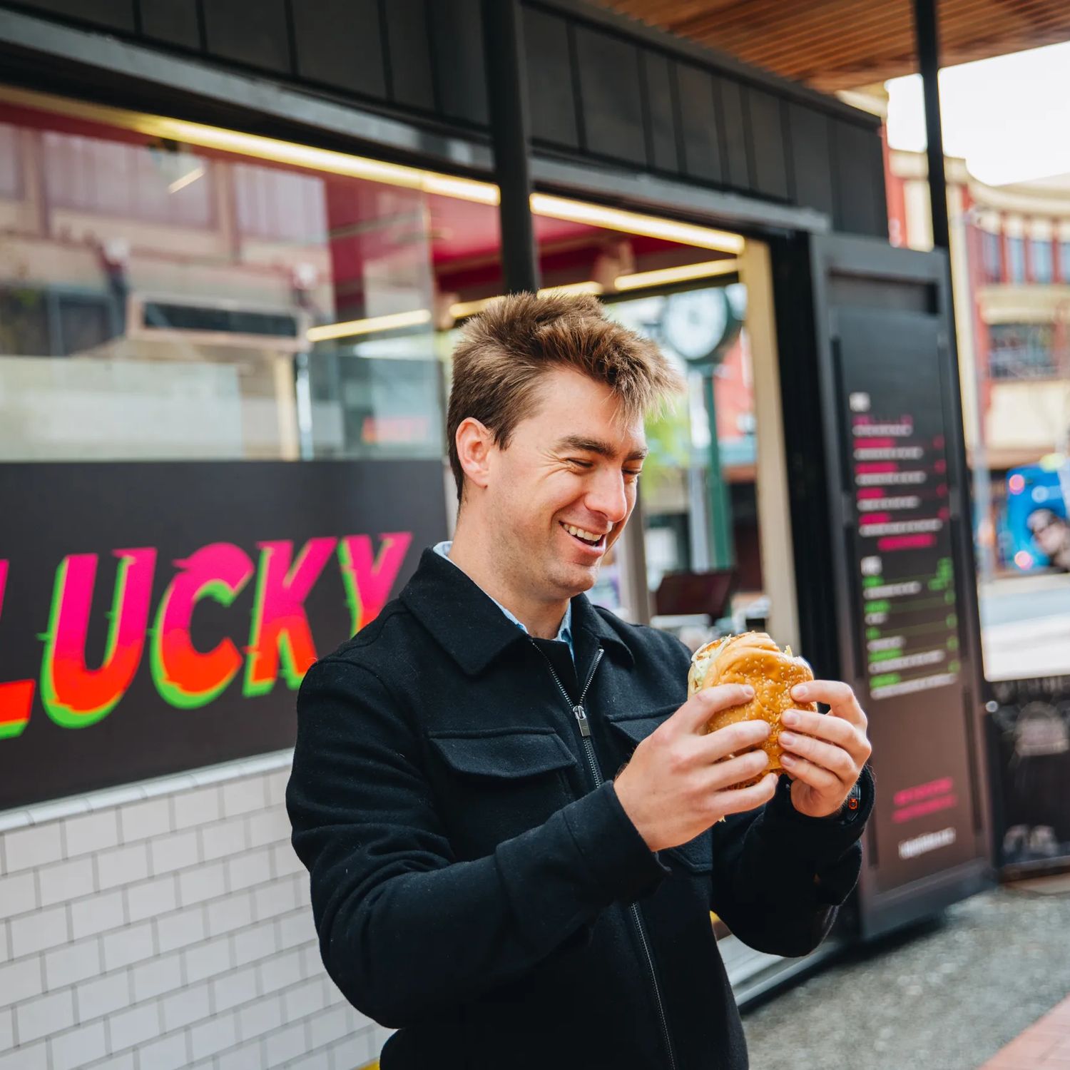 A person smiling at a burger outside Lucky on Courtenay Place