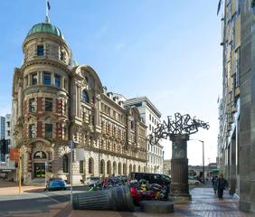 The Public Trust Hall building in Wellington, New Zealand. It's an example of Edwardian Baroque architecture with beige and red bricks and a small turret on the corner with a copper dome.