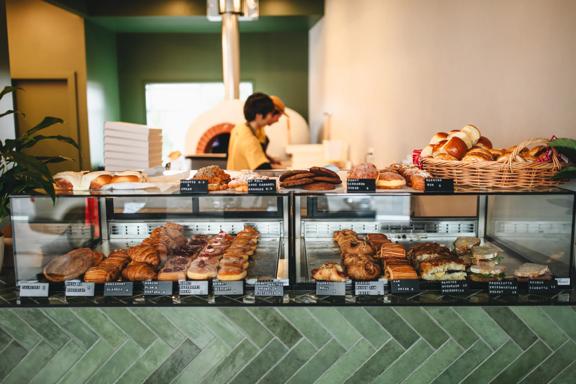 The front counter at a bakery with sandwiches, pastries and other baked goods on display.