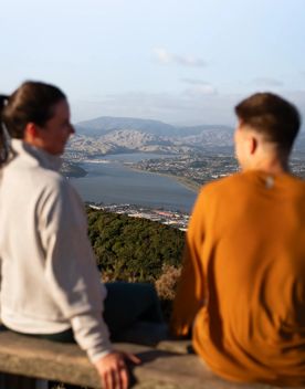 Two people sit on the bench at the Rangituhi Lookout.