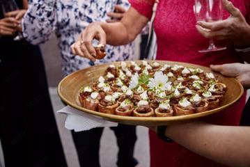 A platter of sausage roll appetizers is being handed out at an event.