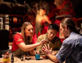 Three people apply fake blood to their hands to learn about special effects for film at the Wētā Workshops.