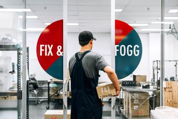 Person holding a box of Fix a& Fogg Peanut butter in the factory.