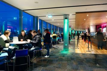 The mezzanine bar at the Hnry Stadium Function centre, where people are enjoying drinks overlooking the rugby game.