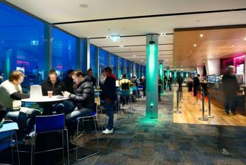 The mezzanine bar inside Sky Stadium Function centre, where people are enjoying drinks overlooking the rugby game.