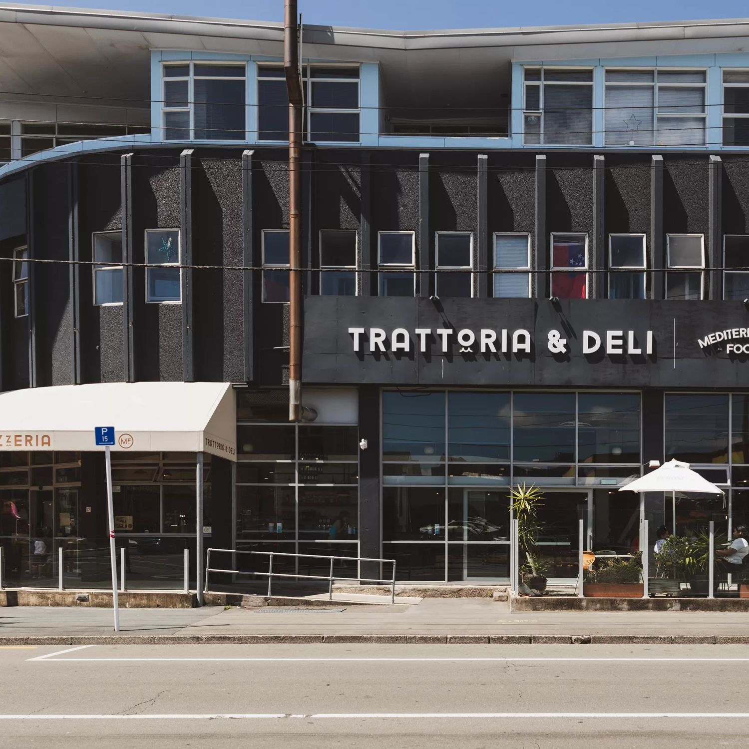 The exterior of Mediterranean Foods Trattoria & Deli in Newtown, Wellington. It's a black building with a white awning.