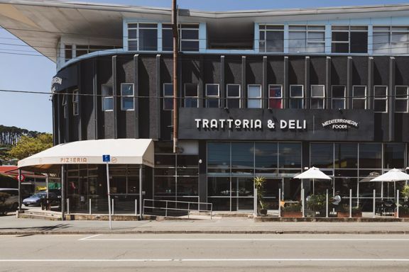 The exterior of Mediterranean Foods Trattoria & Deli in Newtown, Wellington. It's a black building with a white awning.