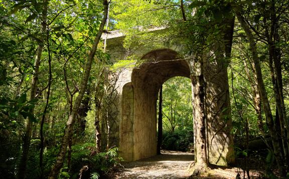 A large minument sits between trees and bush on the Kaitoke regional park trail.