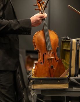 A musician takes their viola out of its carrying case.