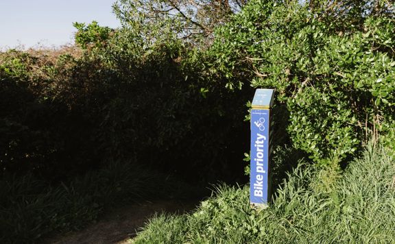 Blue 'Bike Priority' marker post on a section of the Jail Brake track at Centennial Reserve.