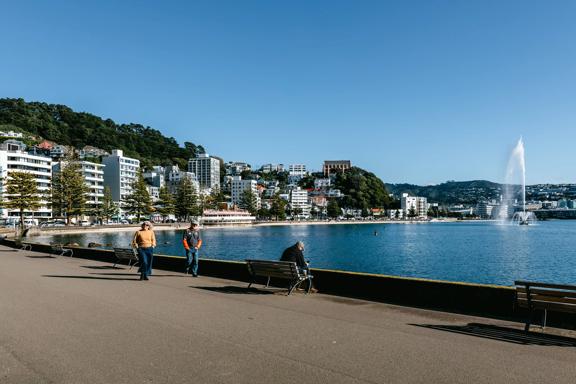 Looking towards Oriental bay with people walking along the waterfront and the fountain going in the water.