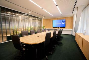 The executive boardroom at Generator Bowen Campus has a large table with 14 chairs. One wall is glass panels.