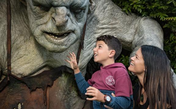 A child and adult admire a statue of a Troll from the Lord of the Rings Saga while on a Wētā Cave and Workshop Tour.