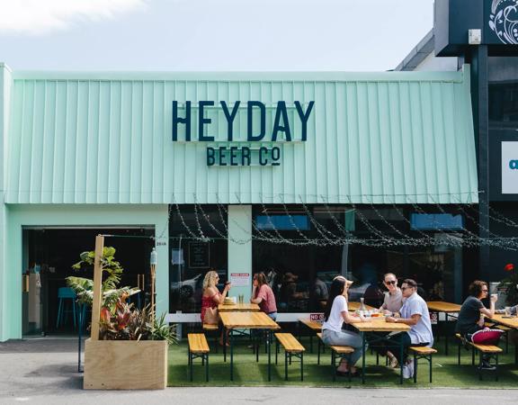 The front facade of Heyday Beer Co. on Upper Cuba Street in Te Aro Wellington. People enjoy drinks at the picnic tables on the front patio.