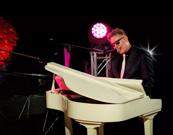 Cam & Same, a New Zealand based tribute band, dressed as Billy Joel and Elton John playing piano and singing on stage.