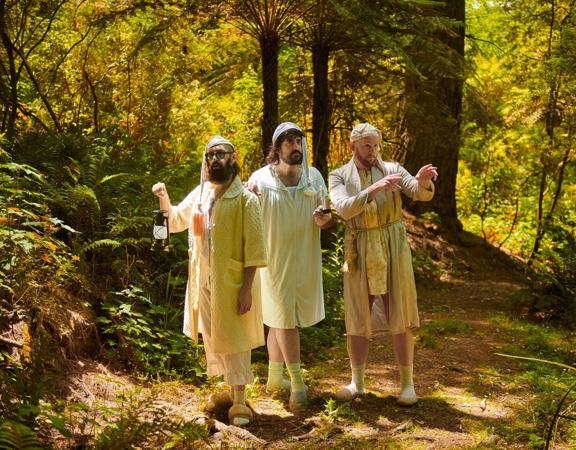 The three members of Aunty Donna, a Melbourne-based comedy trio, stand in the woods dressed in sleeping gowns.