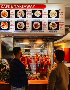 Two friends looking at the menu on the board at K C Cafe & Takeaway.