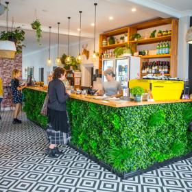 The interior of The Botanist in Lyall Bay. The counter has a fake bush attached, and the floor is a black and white pattern.