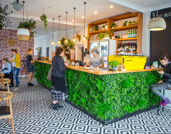 The interior of The Botanist in Lyall Bay. The counter has a fake bush attached, and the floor is a black and white pattern.