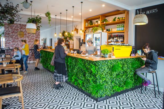 The interior of The Botanist in Lyall Bay. The counter has a fake bush attached, and the floor is a black and white pattern.