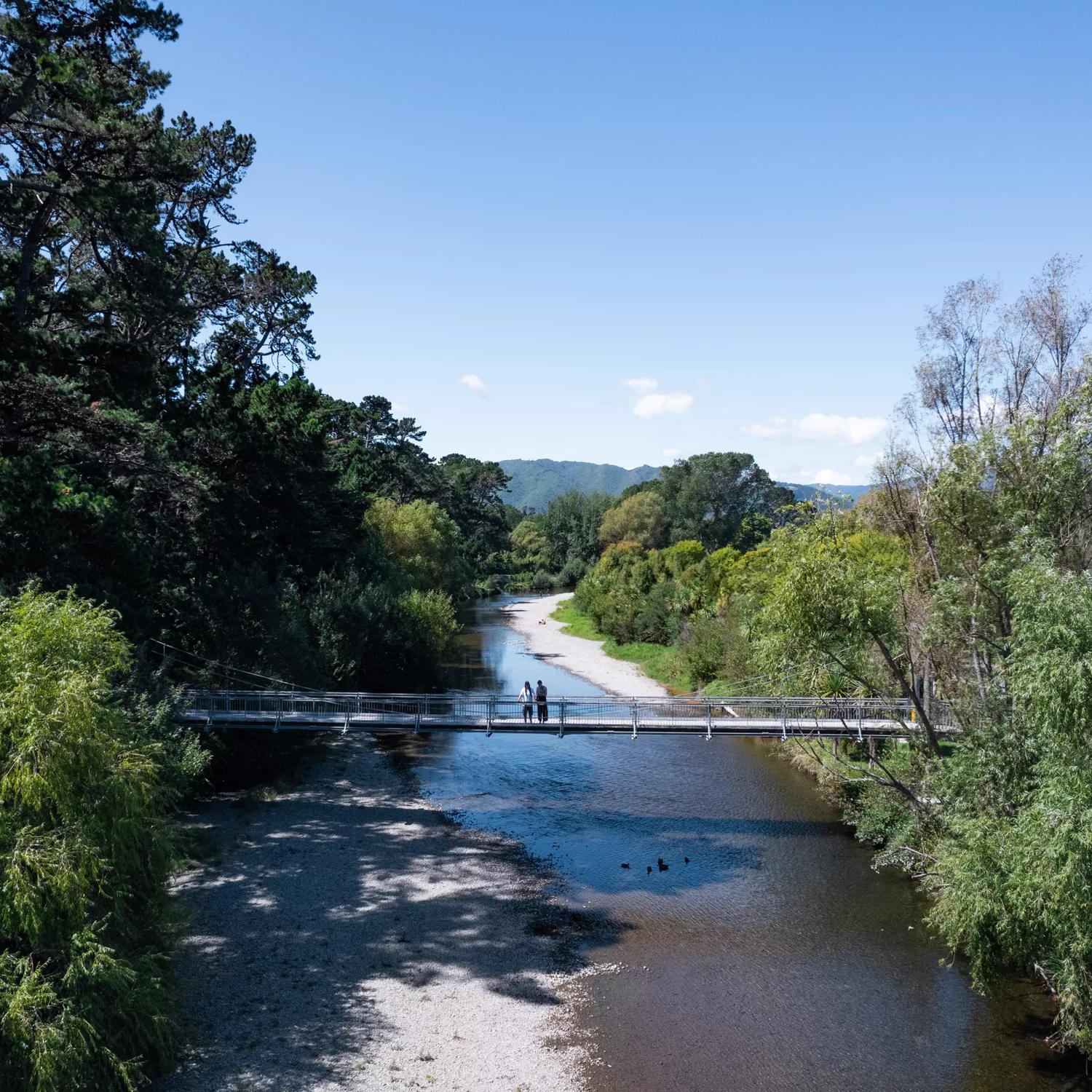 Two people are on a bridge on the Waikanae River Trail in Kāpiti Coast, New Zealand.