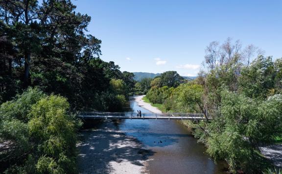 Two people are on a bridge on the Waikanae River Trail in Kāpiti Coast, New Zealand.