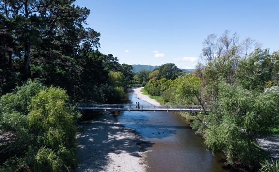 Two people are on a bridge on the Waikanae River Trail in Kāpiti Coast, New Zealand.
