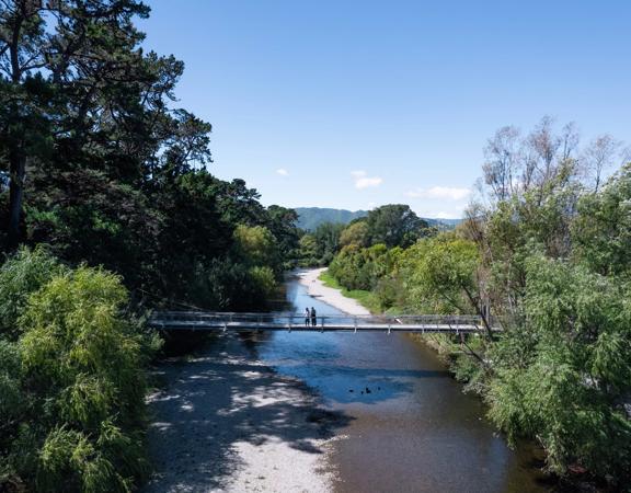 Two people are on a bridge on the Waikanae River Trail in Kāpiti Coast, New Zealand.