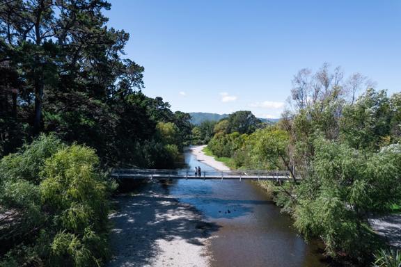 Two people are on a bridge on the Waikanae River Trail in Kāpiti Coast, New Zealand.